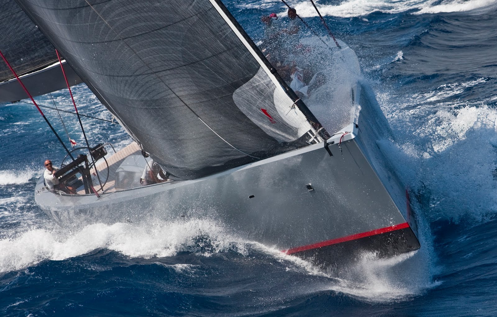 Sportliche graue Segelyacht unter Segeln mit Gischt am Bug